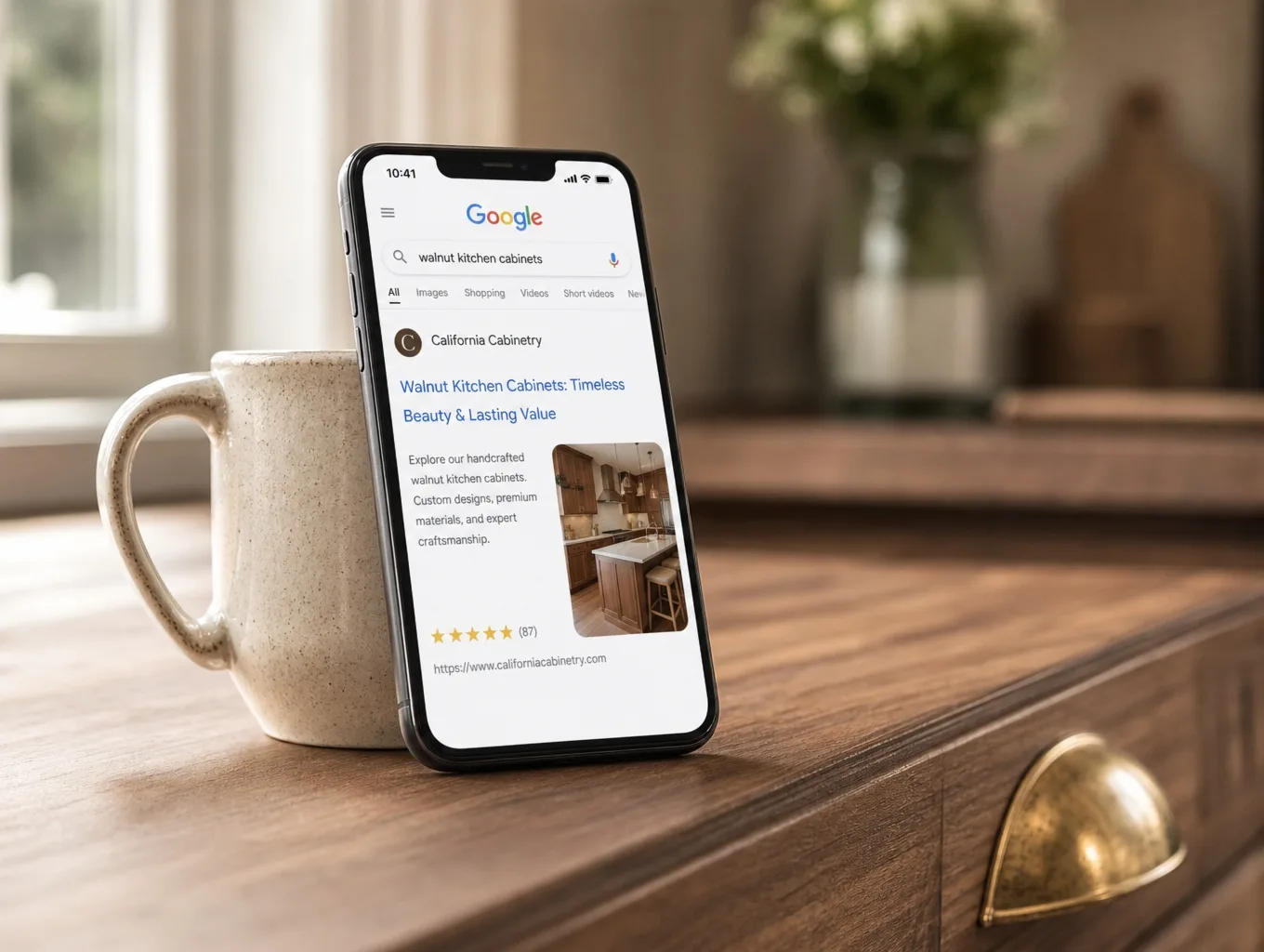 A phone on a walnut counter showing a Google search result for a kitchen company at the top of the page
